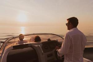 um casal sênior em roupas casuais com seu filho desfruta enquanto andava de barco no mar ao pôr do sol. o conceito de uma família feliz. foco seletivo foto