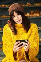 linda morena europeia vestida com um suéter de lã amarelo e chapéu do lado de fora. a linda garota que usa roupas de outono elegantes grossas em clima frio. foto