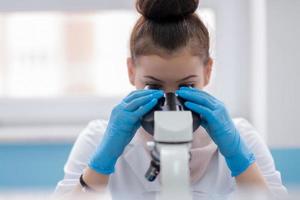 cientista estudante feminina olhando através de um microscópio foto