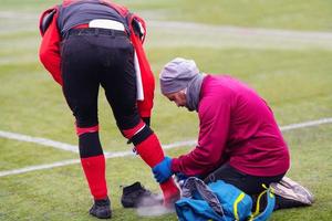 médico esportivo usando spray de congelamento ao tratar desportista ferido foto