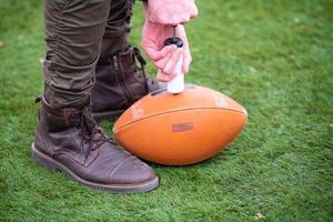 homem bombeando ar na bola de futebol americano foto