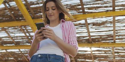 mulher de smartphone mandando mensagens no celular na praia foto