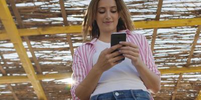 mulher de smartphone mandando mensagens no celular na praia foto