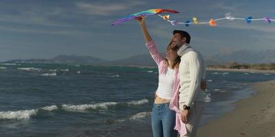 casal feliz se divertindo com pipa na praia foto