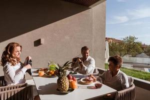 casal sênior e seu filho tomando um café da manhã saudável juntos no início da manhã em uma casa de luxo. foco seletivo foto