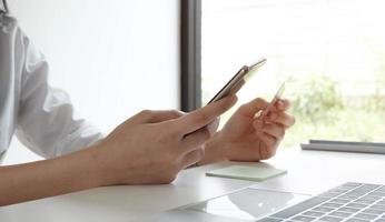 mulher segurando smartphone e cartão de crédito foto