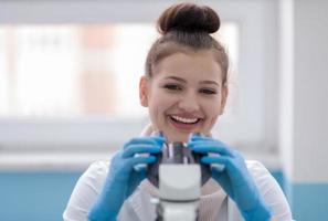 cientista estudante feminina olhando através de um microscópio foto