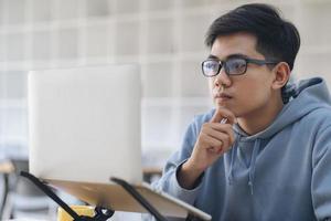 jovem estudante de colagem usando computador para estudar online foto
