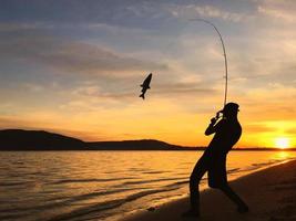 jovem pescando ao pôr do sol foto