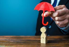 agente de seguros detém um guarda-chuva sobre um homem com um crack. reabilitação após trauma, drogas, álcool. seguro de saúde e vida. ajuda psicológica. suporte social. recuperação. protetorado, patronato foto