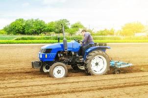 um agricultor caucasiano branco em um trator fazendo linhas de cumes e montes em um campo agrícola. preparando a terra para o plantio de plantas de culturas futuras. cultivo de solo para plantio. agroindústria, agronegócio. foto