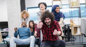 equipe de negócios multiétnica competindo em cadeiras de escritório foto