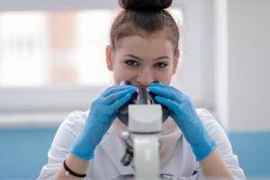 cientista estudante feminina olhando através de um microscópio foto