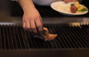 mãos de chef cozinhando peixe salmão grelhado foto