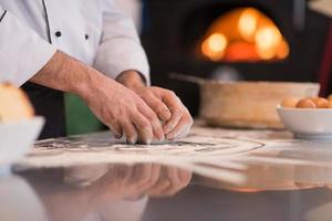 mãos de chef preparando massa para pizza foto