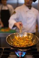 chef lançando legumes no wok foto