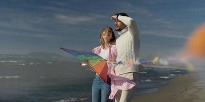 casal feliz se divertindo com pipa na praia foto