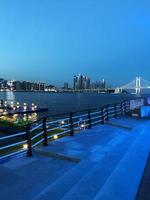 rua noturna da cidade de busan. meios de aterro e arbustos. luzes da cidade à noite foto