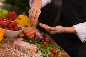 chef colocando sal na suculenta fatia de bife cru foto