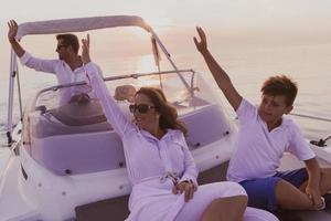 um casal sênior em roupas casuais com seu filho desfruta enquanto andava de barco no mar ao pôr do sol. o conceito de uma família feliz. foco seletivo foto