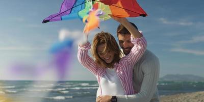 casal feliz se divertindo com pipa na praia foto