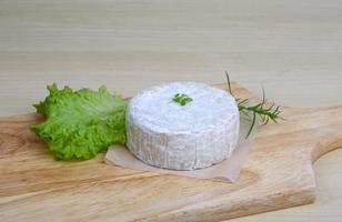 queijo camembert na tábua de madeira e fundo de madeira foto