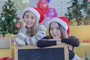 duas mulheres posando com gorros de papai noel foto