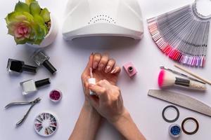 conceito de arte de unhas. mulher dando-se manicure em fundo branco foto