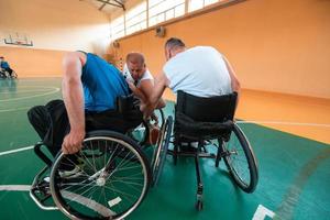 Veteranos de guerra com deficiência equipes de basquete de raça mista e idade em cadeiras de rodas jogando uma partida de treinamento em um ginásio de esportes. conceito de reabilitação e inclusão de pessoas com deficiência foto