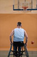 um inválido de guerra em uma cadeira de rodas treina com uma bola em um clube de basquete em treinamento com equipamentos esportivos profissionais para deficientes. o conceito de esporte para pessoas com deficiência foto