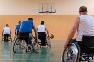 veteranos de guerra deficientes em cadeiras de rodas com equipamento profissional jogam basquete no salão. o conceito de esportes com deficiência foto