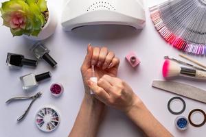 conceito de arte de unhas. mulher dando-se manicure em fundo branco foto