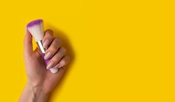 mãos femininas com uma bela manicure em um fundo amarelo, vista superior foto