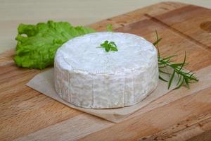 queijo camembert na tábua de madeira e fundo de madeira foto