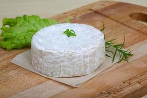 queijo camembert na tábua de madeira e fundo de madeira foto