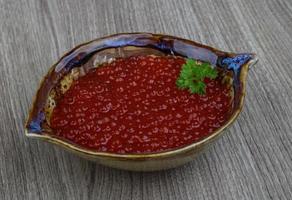 caviar vermelho em uma tigela sobre fundo de madeira foto