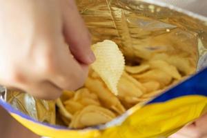 mão segure batatas fritas com saco de lanche foto