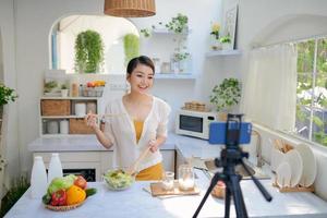 blogueiro de comida gravando vídeo com câmera do telefone na cozinha de casa foto