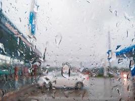 gotas de chuva na frente do para-brisa desfocam o fundo do carro branco no posto de gasolina foto