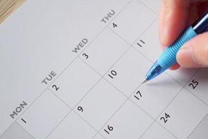 mão de mulher com caneta escrevendo na data do calendário conceito de reunião de planejamento de negócios foto