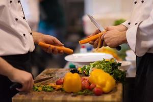 mãos de chefs cortando cenouras foto