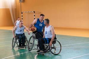 Veteranos de guerra com deficiência, equipes de basquete opostas de raça mista em cadeiras de rodas fotografadas em ação enquanto jogavam uma partida importante em um salão moderno. foto