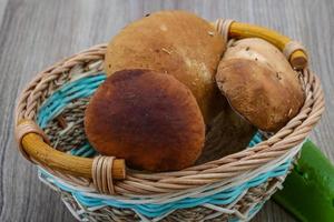 cogumelos selvagens em uma cesta em fundo de madeira foto