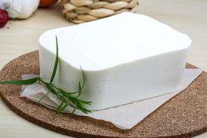 queijo feta na tábua de madeira e fundo de madeira foto