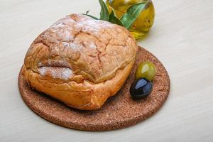 pão ciabatta na tábua de madeira e fundo de madeira foto