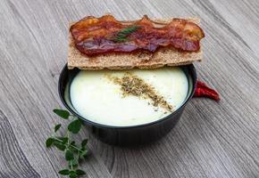 sopa de queijo em uma tigela com fundo de madeira foto