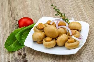 champignon em conserva no prato e fundo de madeira foto