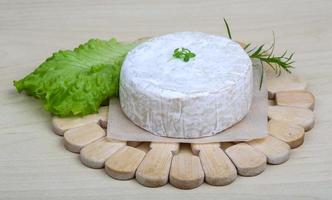 queijo camembert na tábua de madeira e fundo de madeira foto