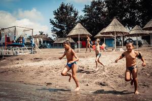 meninos brincalhões se divertindo enquanto correm na praia em dia de verão. foto