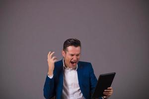 empresário adulto médio gritando enquanto estiver usando o touchpad contra um fundo cinza. foto